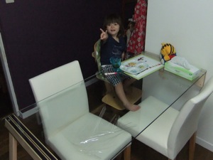 ガラスのテーブルに座っているピース姿の真由喜