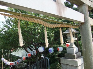 鳥居と注連縄越しに提灯が見える