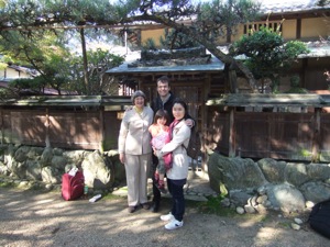 江戸三の部屋の外で 離れの門の前に家族四人が立つ