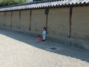 土塀の前に真由喜と玩具の鹿が立つ