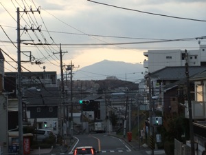 町並みや電線の向こうに雲の下の山が見える