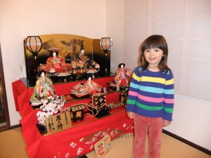 真由喜がお雛様の算段飾りの前に立つ