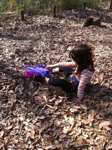 真由喜が落ち葉の中に座って、自分を埋めようとする