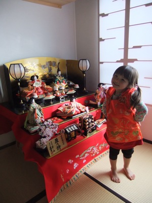 真由喜が算段飾りの雛人形の前に立つ