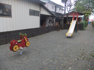 前に遊具があるが、奥に鳥居が辛うじて見える