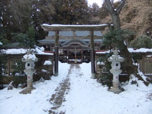 雪の中で、鳥居の無効に社殿が見える。