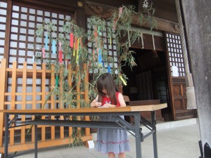 真由喜が社殿の前で願い事を短冊に書き込む