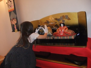 真由喜がお内裏様をお雛様の隣に丁寧に飾っている