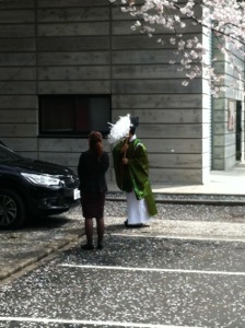 桜の下で神職が車を祓う