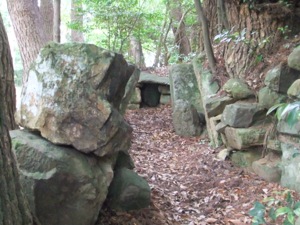 土や天井がなくなった古墳で、石の壁が見える。