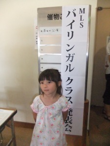 真由喜が発表会の看板の前に立っている