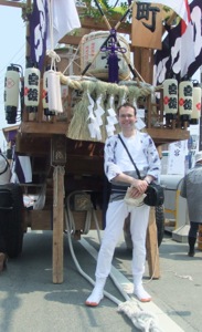 私が股引や腹掛を着て、飾られた石車の前に立つ