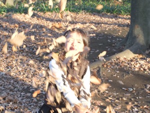 真由喜が落ち葉をカメラに向かって投げる