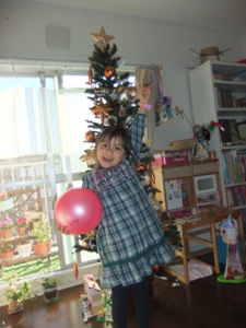 真由喜がクリスマスツリーの前で立って、ほぼ隠す