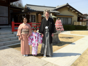 私、ゆり子と真由喜が神社の境内で和装で立つ